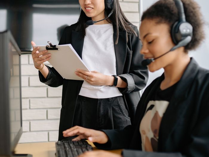 Dos personas atendiendo llamadas de clientes con auriculares