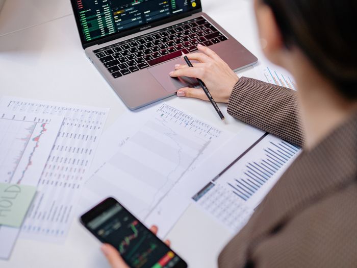 Persona revisando gráficos de ventas en el portátil y el móvil