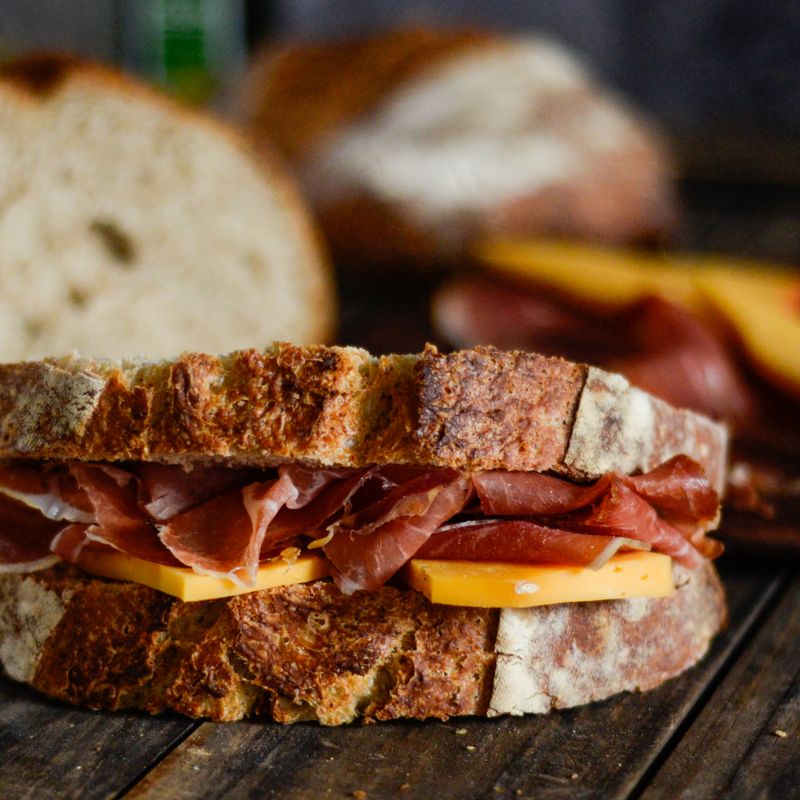 Bocadillo de jamón curado sobre una tabla de madera en un obrador de alimentación