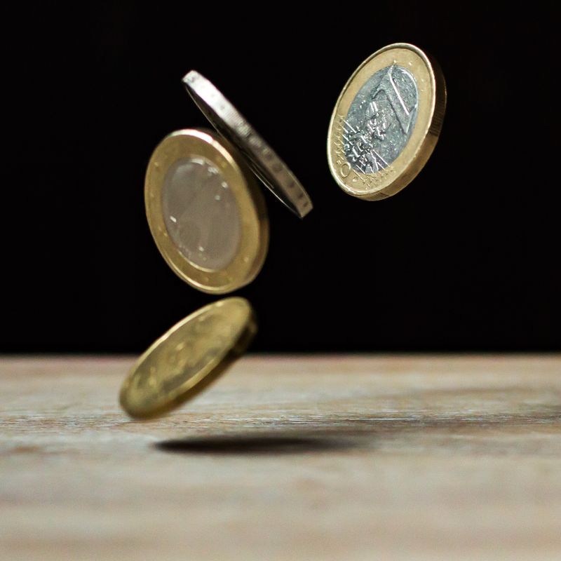 Monedas de euro cayendo sobre una mesa de madera